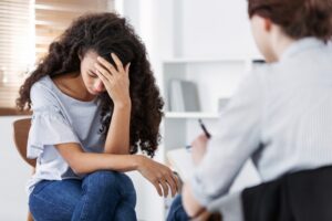 Young sad woman sitting with therapist