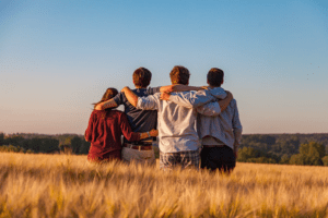 four people enjoying a group hug in a field