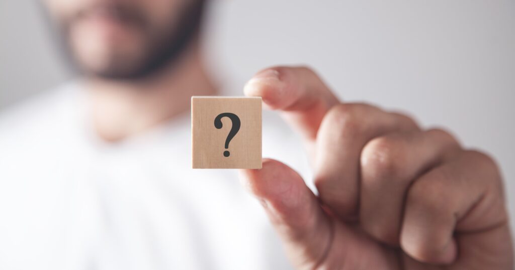 Man showing question mark on wooden cube.